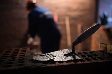 professional construction worker laying bricks and building barbecue in industrial site. Detail of hand adjusting