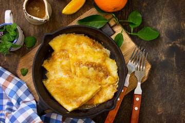 Homemade French pancakes - Crepe Suzette with orange syrup for a delicious breakfast. Top view flat lay background with copy space.