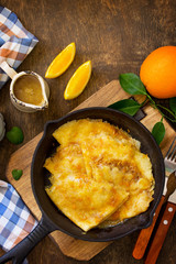Homemade French pancakes - Crepe Suzette with orange syrup for a delicious breakfast. Top view flat lay background with copy space.