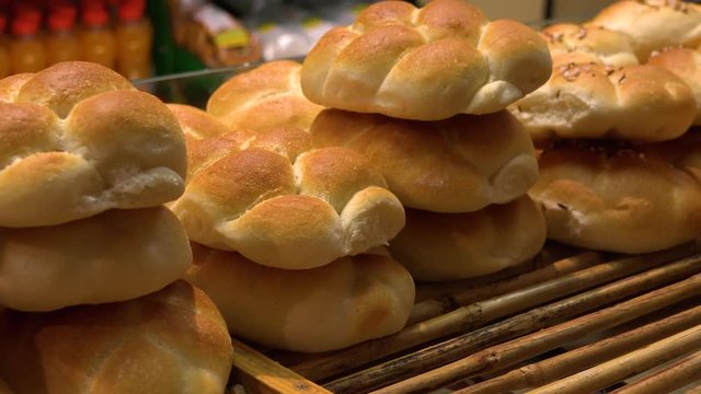 A baker puts bread rolls on a shelf in a bakery - closeup