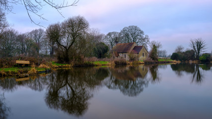 Sunrise over St Leonard's church and Hartley Mauditt pond, near Alton, in the South Downs national park, Hampshire, UK