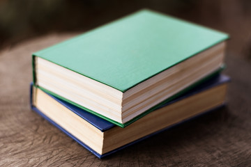 Green and blue books on a felled tree. Two books on hemp