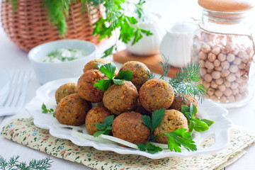 Chickpea falafel with fresh herbs on a white table, horizontal