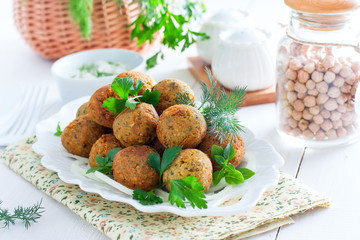 Chickpea falafel with fresh herbs on a white table, horizontal