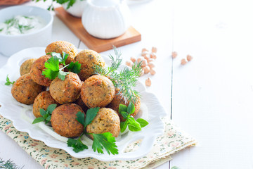Chickpea falafel with fresh herbs on a white table, horizontal, copy space