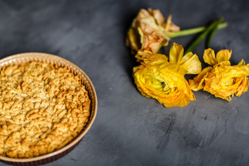 Yellow flower, cookies and apple pie lying on gray background