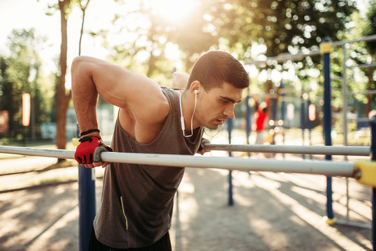 Male athlete exercises on parallel bars outdoor