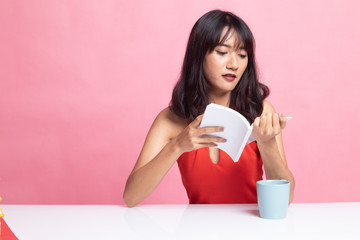 Young Asian woman read a book with cup of coffee.