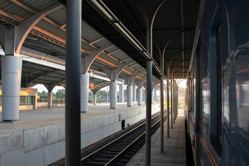 Photo of passenger platform with train stop on the railway station at sunset 