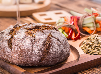 A fresh round of dark bread on a wooden plate