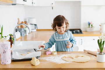 Little girl preparing easter cookies at the kitchen.