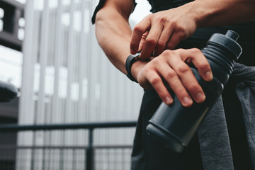 Man with water bottle using a smartwatch to monitor his progress