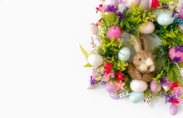 easter wreath with colorful eggs and flowers and a rabbit in the center