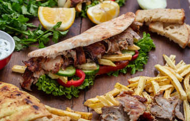 Gyros, shawarma, take away, street food.  Sandwich with meat on wooden table