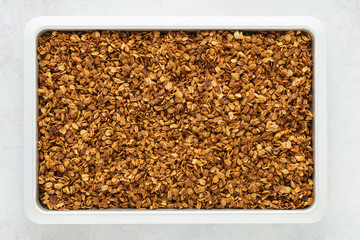 Homemade healthy granola with oats, nuts and honey on a tray.