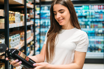 Woman choosing wine in alcohol section in market