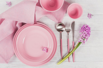Pink rustic place setting with purple hyacinth flower and linen napkin on white wooden background