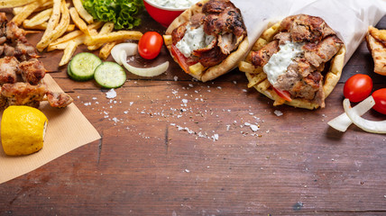 Fototapeta premium Gyro pita, shawarma, souvlaki. Two pita bread wraps and meat skewers on wooden table