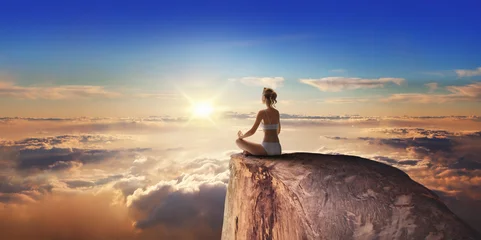 Abwaschbare Fototapete above the clouds - Young woman at sunrise in lotus pose © Igor Link