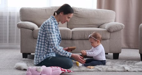 Mother and her baby girl playing with toy on carpet in the living room