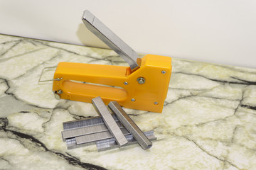 Large stapler and staples for construction work on white .