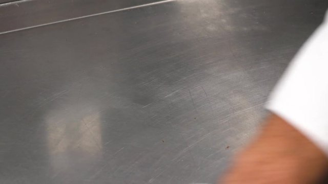 A man cleans a metallic kitchen counter with a rag - closeup
