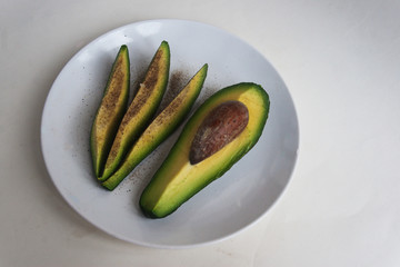Avocado slices with salt and pepper on a plate. Candid.