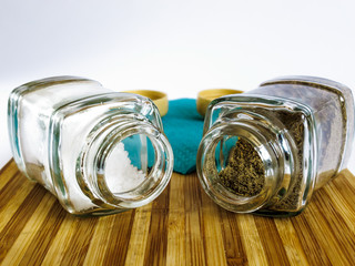 Salt and pepper in a glass shaker and pepper shaker stand on a cutting board
