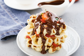 Belgium waffles with strawberries, banana and flowing chocolate.