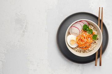 Bowl of veggie noodle broth ramen with egg, carrot, radish and sesam