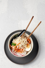 Bowl of veggie noodle broth ramen with egg, carrot, radish and sesam