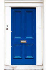 SImple and elegant old fashioned blue house door with a bronze letterbox and a white frame