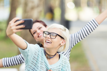 Young beautiful female students taking selfies outdoors in campus