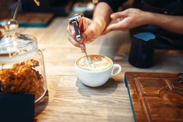 Barista makes drawing with foam, coffee making