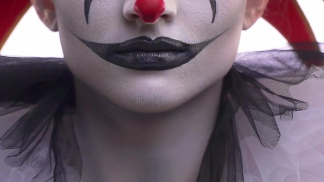 Close up of a jesters mouth, black and white makeup, flexing jaw muscles