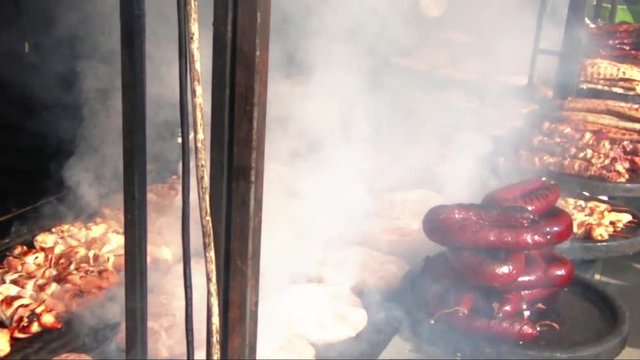 Smoke cloud over a big barbecue with bread and sausages