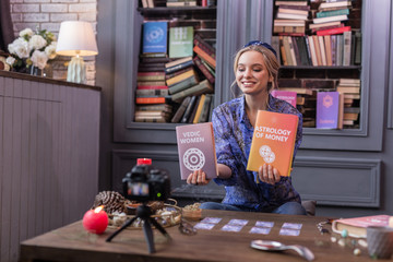 Positive joyful young woman holding two books