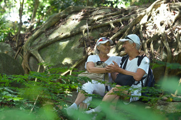 Naklejka na ściany i meble Portrait of elderly couple resting in tropical garden outdoors