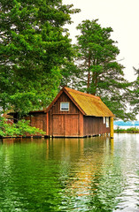 Old wooden boathouse under trees at Schwerin lake. Mecklenburg-Western Pomerania, Germany