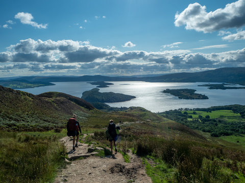  two girls hiking with beautiful lake (loch lomond) and green landscape