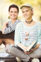 Young beautiful students(one with flower tights) sitting on a bench in campus