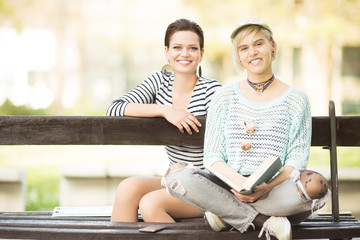 Young female students(one with flower tights) sitting on a bench in campus