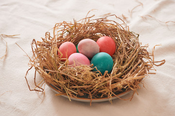 Beautiful Easter multi color egg in straw on wooden background, Easter day concept