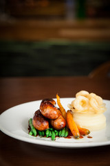 Beautifully presented sausages, mashed potato, carrots and green beans