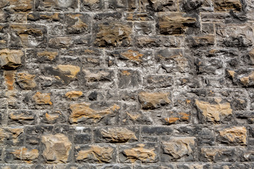 Closeup of a weathered rough textured industry stone brick  wall outdoors.