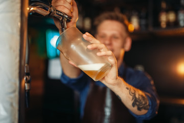 Male barman pouring beer at the bar counter