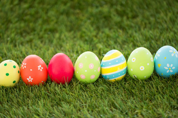 Fototapeta na wymiar easter, holidays and tradition concept - row of colored eggs on artificial grass