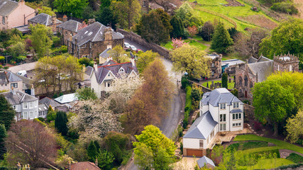 Top view of a Scottish village landscape with cherry blossom trees and houses with green grass...