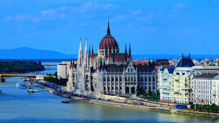Hungarian parliament building view from other bank of river Danube with light clouds at sky, selective focus