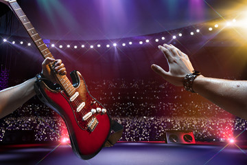 Rock star on the main stage big music festival. Aroun full stadium of spectators. fans are holding...